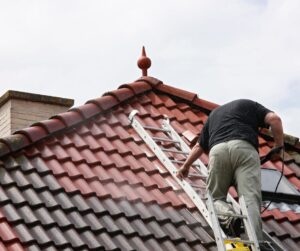 Man power washing dirty roof tile of home